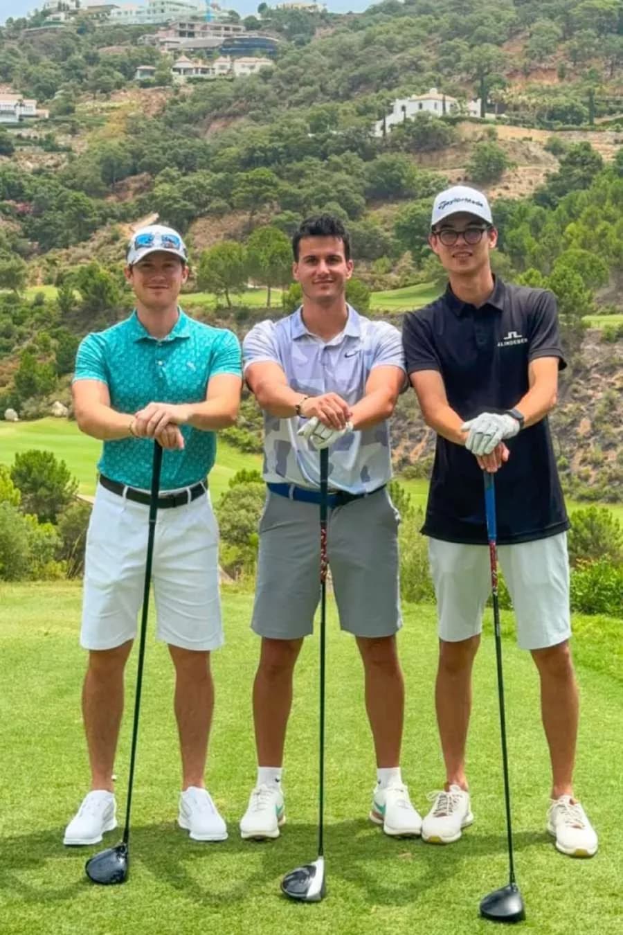 I tre di Bravo Golf appoggiati ai driver sul tee, con le colline sullo sfondo